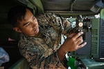 Marine Corps Lance Cpl. Issac Nakai, a field radio operator for the II Marine Expeditionary Force Information Group, works on a radio inside a Humvee at Camp Lejeune, North Carolina, Nov. 2, 2020. The Defense Logistics Agency partners with weapons system program offices and service engineering activities to qualify small businesses for sourcing parts as field radio battery chargers that have high demand but limited availability. Photo by Marine Corps Lance Cpl. Henry Rodriguez