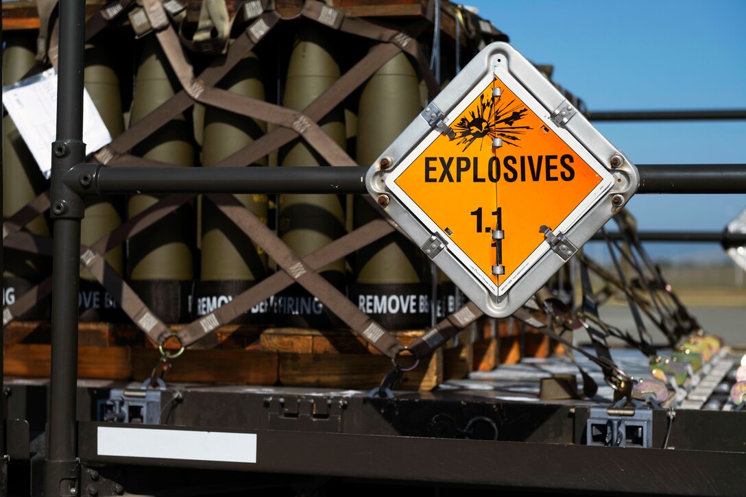 Munitions sit on pallets marked with an explosive sign.