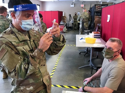 U.S. Air Force Capt. Alejandro Bautista readies a COVID-19 vaccination for U.S. Army Sgt Maj. Joseph Fisher at the Camp Smith Training Site Medical Readiness Clinic, N.Y., Dec.16, 2020. The New York Army National Guard was recently recognized for having the best overall medical readiness for large state forces during fiscal 2021.