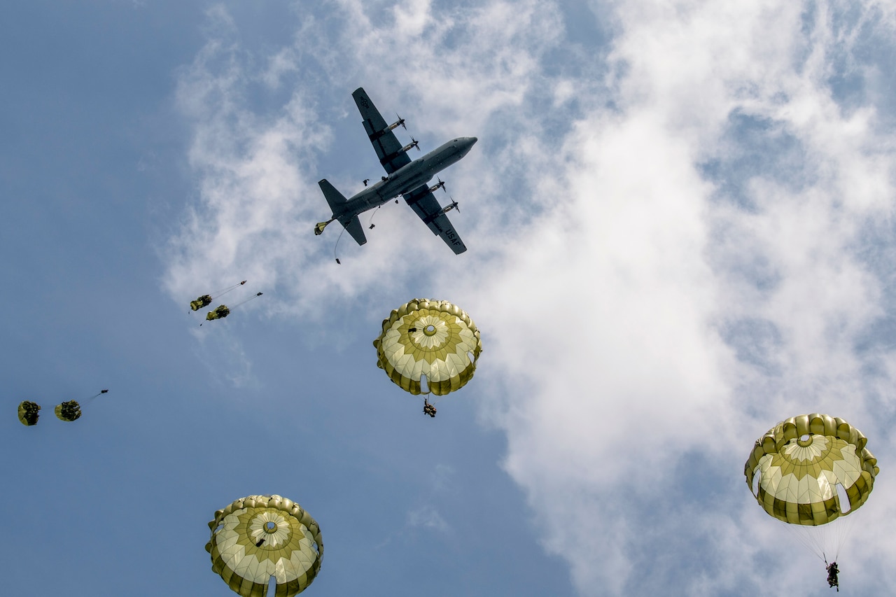 Soldiers freefall with parachutes after jumping out of an aircraft.