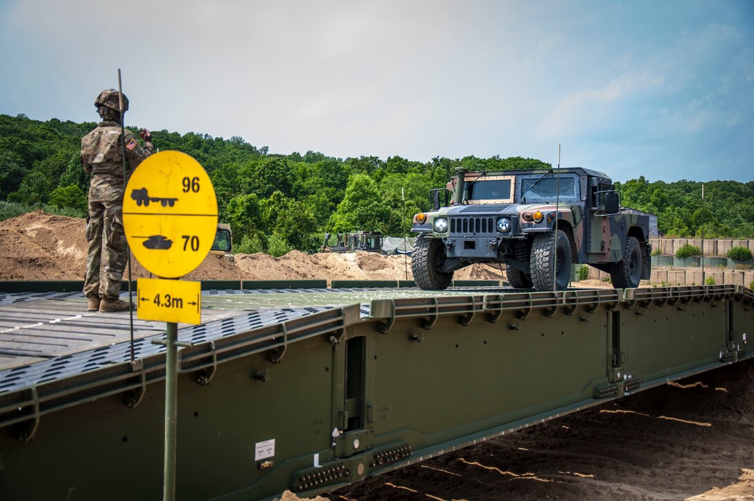 A Soldier assigned to the Connecticut National Guard's 250th Multi-Role Bridge Company ground guide’s a Humvee across the unit’s Dry Support Bridge they constructed at Stones Ranch Military Reservation, June, 10, 2020. The DSB is a static bridge that allows military units to cross gaps in terrains up to nearly 151 feet wide.