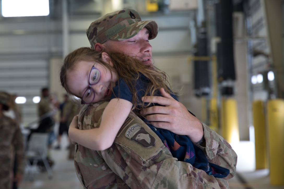 A soldier hugs his daughter.