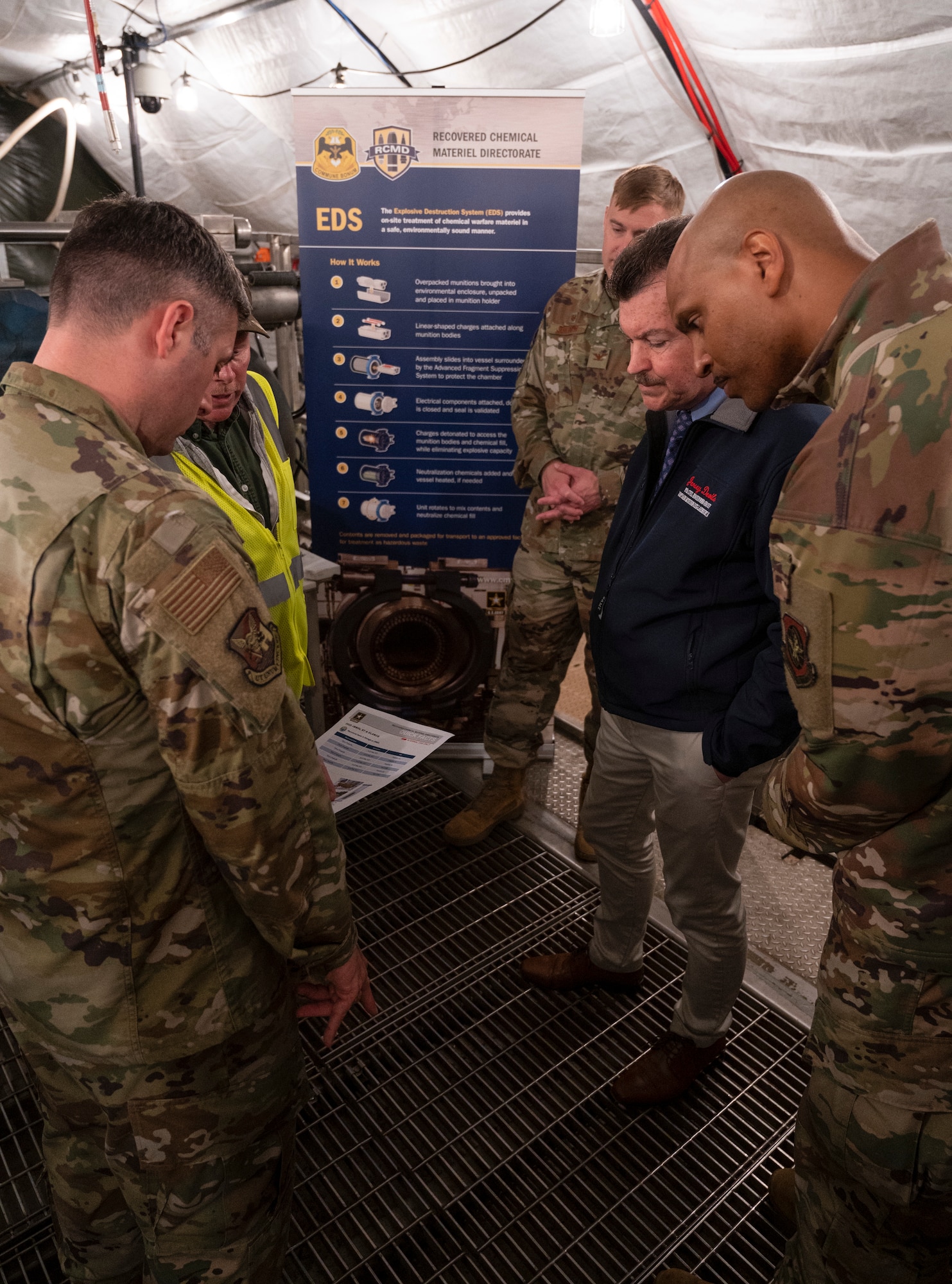 Joint Base McGuire-Dix-Lakehurst leadership read a fact sheet while briefed on the process of explosive destruction and assessments during a tour of the destruction site hosted by the Recovered Chemical Materiel Directorate, May 2, 2022, on Joint Base MDL, New Jersey. RCMA partnered with Joint Base MDL for a second mission to destroy World War I-era chemical munitions after discovering a six 75mm projectiles at Joint Base MDL’s Parachute Jump Circle while investigating and removing chemical munitions, munitions of explosive concern and/or munitions constituents from two disposal pits. (U.S. Air Force photo by Sraff Sgt. Ariel Owings)