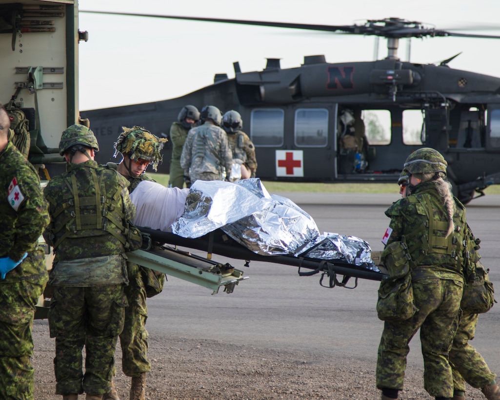 Soldiers from the Nebraska Army National Guard's Company G, 2-104th Aviation Regiment (General Support Aviation Battalion) – along with Cpl. Vanessa O’Gorman, a medical technician with the 1 Canadian Field Hospital – help transport a simulated wounded patient from a UH-60 Blackhawk helicopter during a medical evacuation training mission exercise, May 14, to ambulances and crews from Canada’s 5 Field Ambulance for transport to a Unit Medical Station. O’Gorman spent the majority of the two-week exercise training with Sgt. Jason Dillon, a flight medic from Seward, Nebraska, and Sgt. Raymond Smith, a crew chief from Lincoln, Nebraska, learning how American forces conduct air medical evacuations. More than 150 Soldiers from the Nebraska Army National Guard’s 1-376th Aviation Regiment traveled to Camp Wainwright in Alberta, Canada, May 8-24, for Exercise Maple Resolve 2018, the Canadian Army’s most comprehensive annual training event designed for any contingency operation. This year’s Maple Resolve included approximately 6,000 service members from Canada, the United States, the United Kingdom, Australia and France. Working with Canadian Armed Forces, primarily from 5 Canadian Mechanized Brigade Group (5 CMBG), Nebraska’s aviation battalion served two primary missions, including 24-hour medical evacuation training and support, and air support to all ground defenses. (Nebraska National Guard photo by Spc. Lisa Crawford)