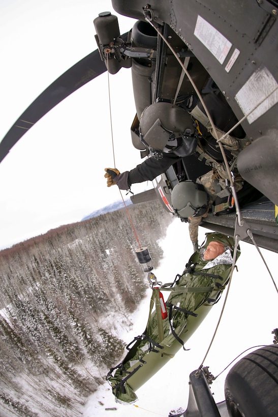 Alaska Army Guard and Staff Sgt. Bradley McKenzie, right, a crew chief, and Staff Sgt. Damion Minchaca, an Army critical care flight paramedic, both with Detachment 2, Golf Company, 2nd General Support Aviation Battalion, 104th Regiment, conduct hoist procedures via a 1st Battalion, 207th Aviation Regiment, UH-60 Black Hawk helicopter, while responding to a simulated medical evacuation at Landing Zone Ranger on Joint Base Elmendorf-Richardson, Alaska.