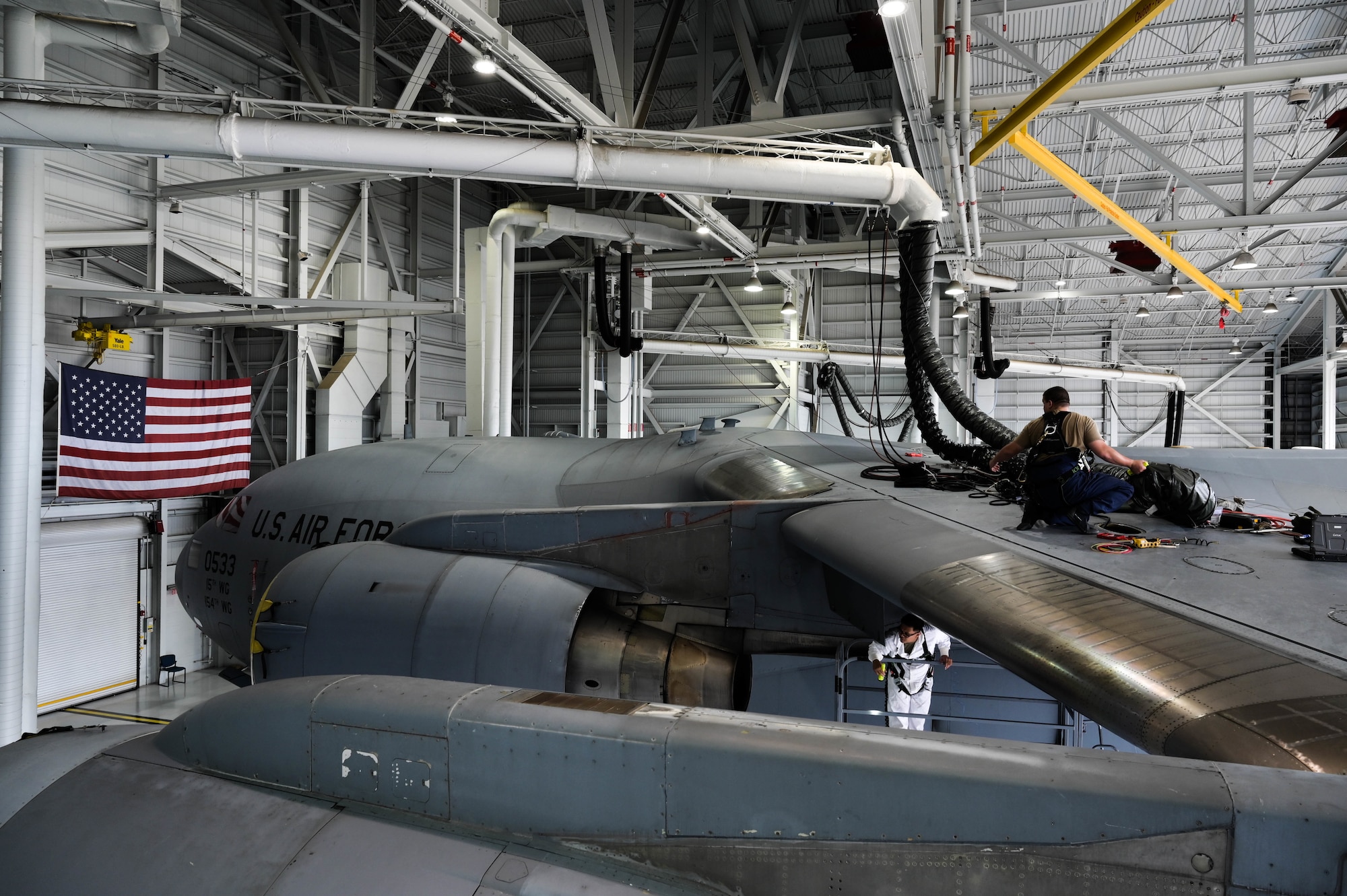 Staff Sgt. Noel Antalan, 154th Maintenance Squadron aircraft fuel systems craftsman, and Senior Airman Sedrick Nelson, 154th MXS aircraft fuel systems journeyman, prepare to pull out their co-worker from the wing of a C-17 Globemaster III during in-tank maintenance at Joint Base Pearl Harbor-Hickam, Hawaii, May 2, 2022. Fuel Airmen take several cautionary measures in order to prevent life-threatening events during maintenance procedures while within the aircraft’s tanks. (U.S. Air Force photo by Staff Sgt. Alan Ricker)