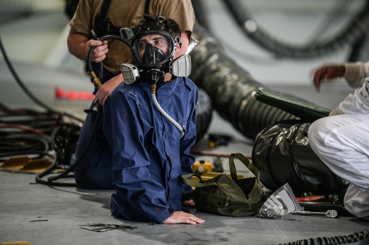 Staff Sgt. Taylor Kuehne, 15th Maintenance Squadron aircraft fuel systems craftsman, enters the wing of a C-17 Globemaster III through an access panel during in-tank maintenance at Joint Base Pearl Harbor-Hickam, Hawaii, May 2, 2022. The procedure requires Kuehne to don a full-face respirator as an increased protection measure in order to operate within the aircraft’s wings. (U.S. Air Force photo by Staff Sgt. Alan Ricker)