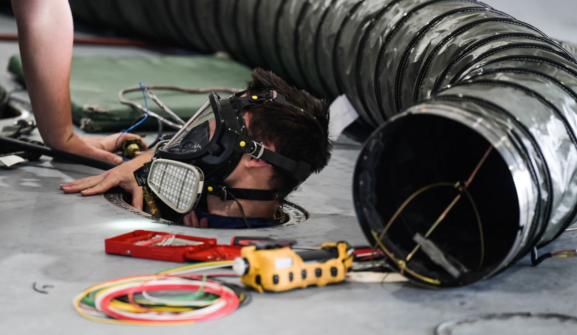 Staff Sgt. Taylor Kuehne, 15th Maintenance Squadron aircraft fuel systems craftsman, exits from the tank of a C-17 Globemaster III from an access panel at Joint Base Pearl Harbor-Hickam, Hawaii, May 2, 2022. In order to access the wing, the tank was depressurized and the fuel was transferred to the right-wing. (U.S. Air Force photo by Staff Sgt. Alan Ricker)