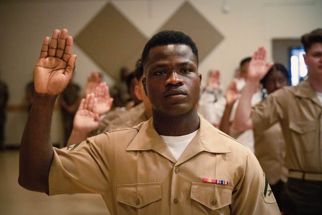 U.S. Marine Corps Lance Cpl. Ricardo Fleuridor, a motor vehicle operator with Headquarters Battalion, 3rd Marine Division, raises his right hand during a naturalization ceremony hosted at the Camp Foster Community Center on Okinawa, Japan, April 25, 2022. A total of 24 U.S. service members from 14 countries swore the Oath of Allegiance and received their Certificates of Naturalization, becoming U.S. citizens. Naturalization is the process by which U.S. citizenship is granted to a foreign citizen after he or she fulfills the requirements to become a citizen established by Congress in the Immigration and Nationality Act of 1965. (U.S. Marine Corps photo by Lance Cpl. Jonathan Beauchamp)