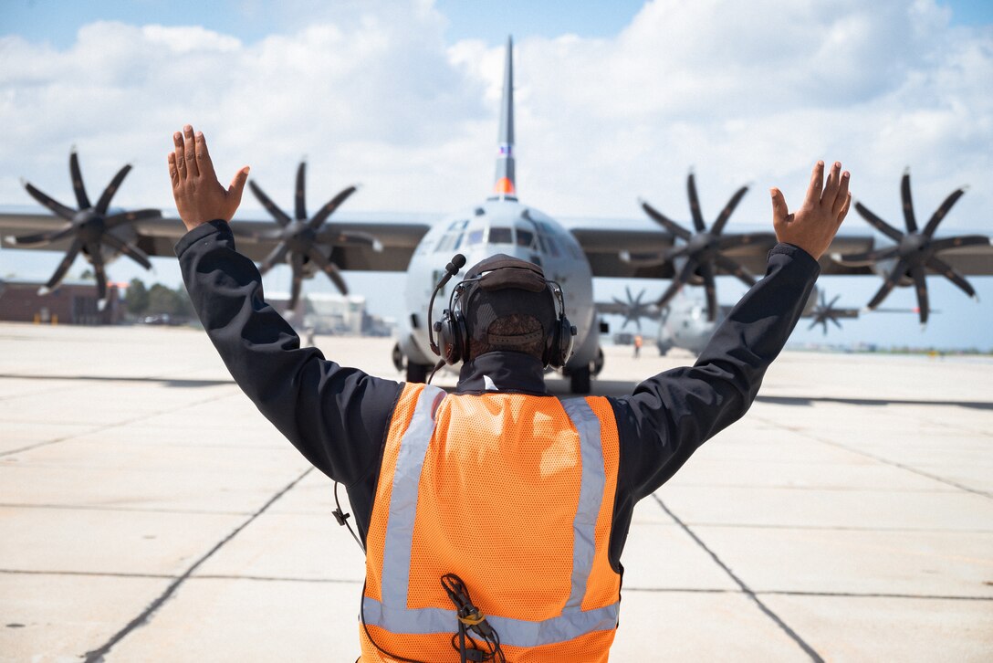 Cameron Seals, a U.S. Forest Service Modular Airborne Firefighting Systems (MAFFS) Airtanker Base Specialist (MABS) trainee, marshalls a Nevada Air National Guard C-130H Hercules during the annual MAFFS Spring Training in Boise, Idaho