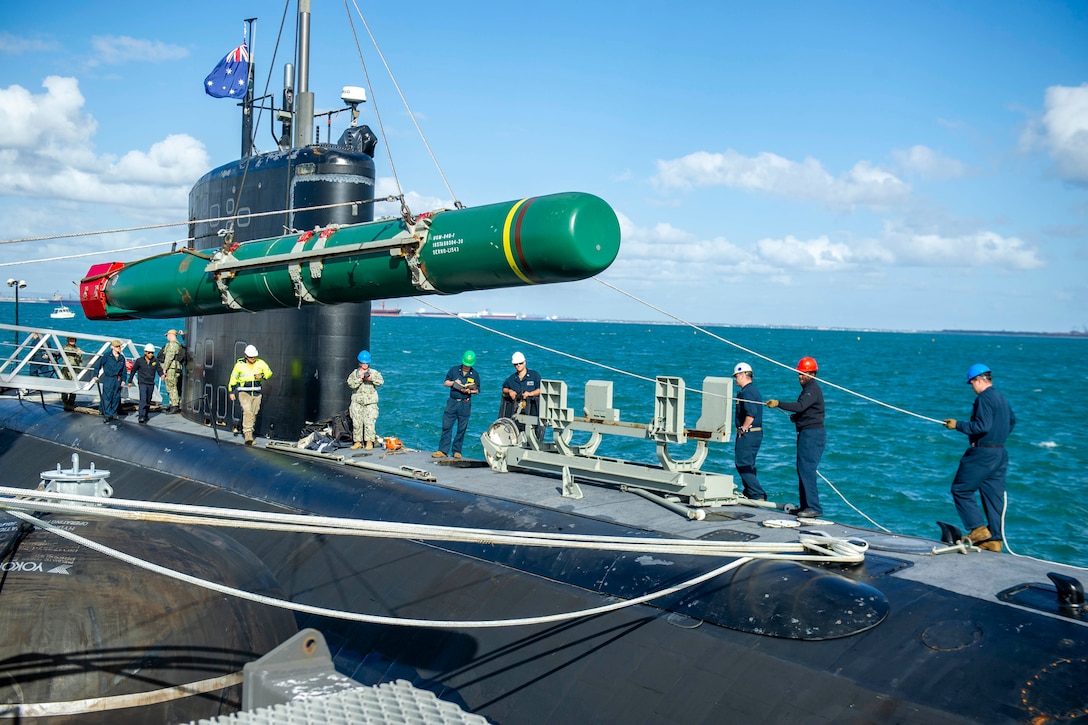 Sailors use ropes and cables to move a large weapon.