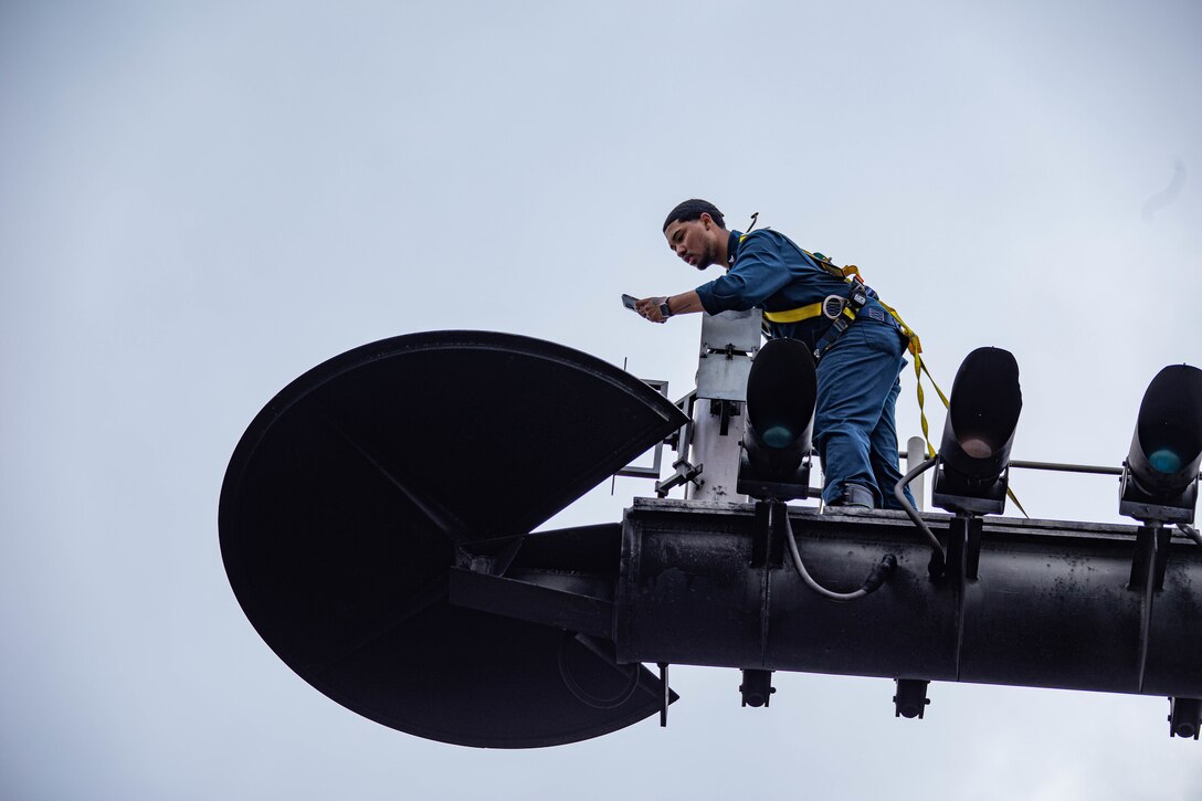 A sailor works on a navigation light.