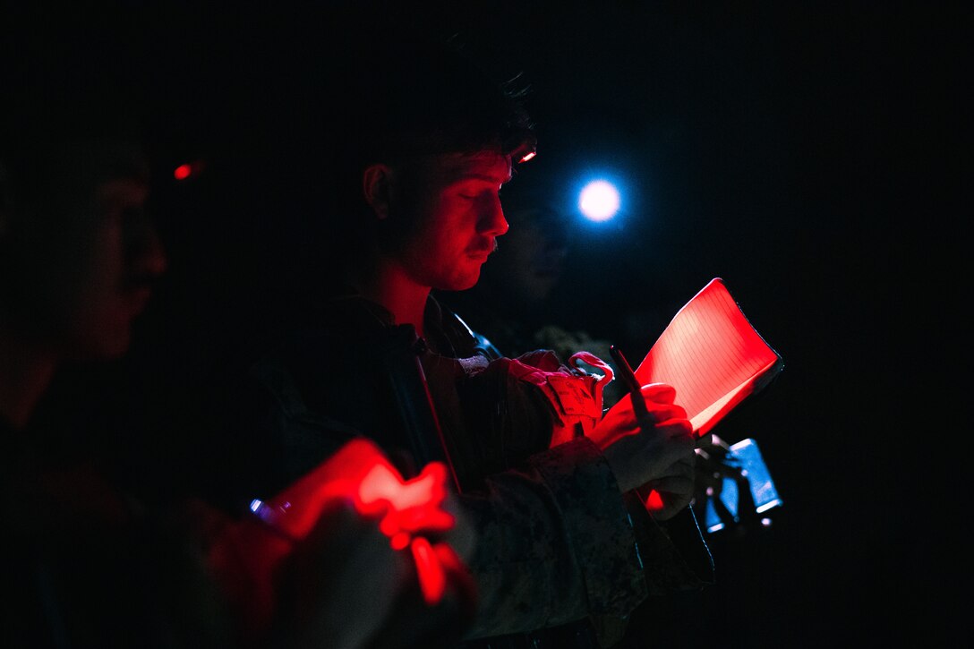 A Marine uses a night light to take notes in the darkness.