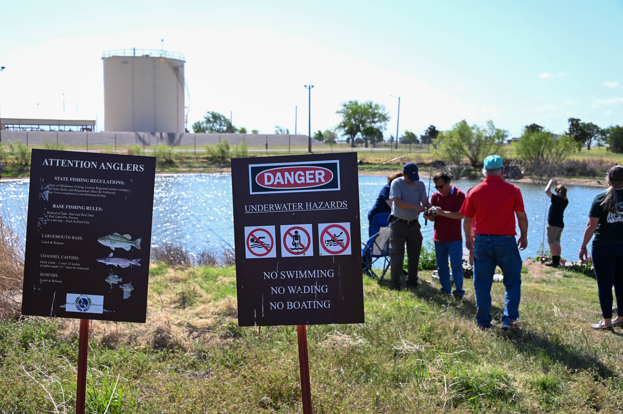 Signs provide information and warnings at the base pond at Altus Air Force Base, Oklahoma, April 29, 2022. The pond was stocked with 800 pounds of channel catfish for the annual fishing derby. (U.S. Air Force photo by Senior Airman Kayla Christenson)