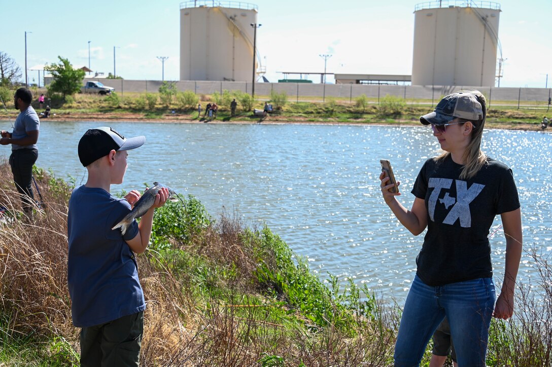 Amanda Hines, a military spouse, takes a photo of her son after catching a catfish during the fishing derby at Altus Air Force Base, Oklahoma, April 29, 2022. Those who caught the biggest, smallest, and specially tagged fish received prize bags of goodies including rods, nets, lures, and tackle boxes. (U.S. Air Force photo by Senior Airman Kayla Christenson)