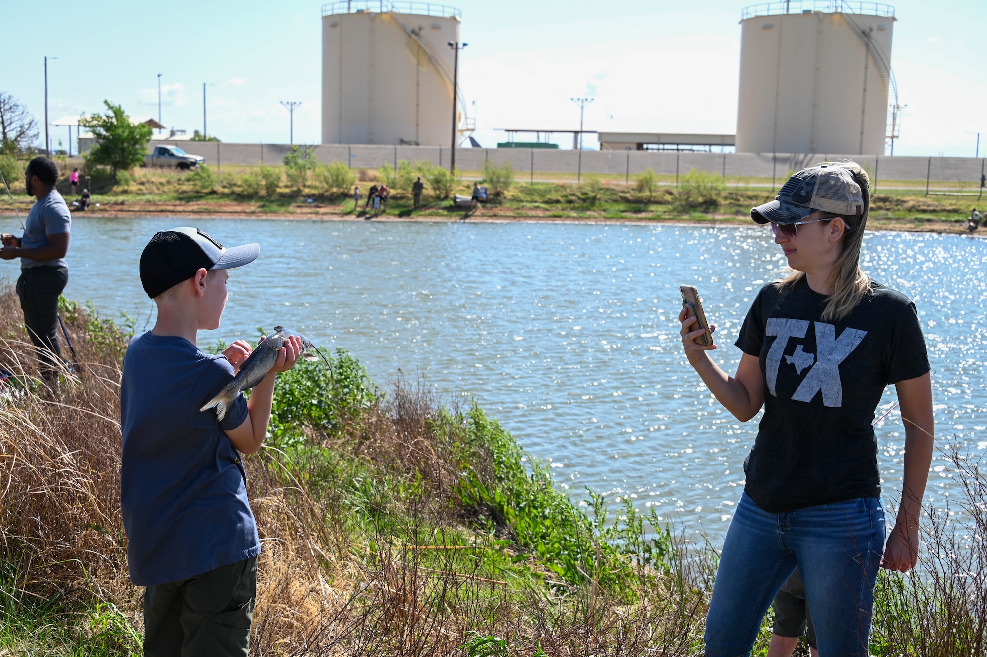 Amanda Hines, a military spouse, takes a photo of her son after catching a catfish during the fishing derby at Altus Air Force Base, Oklahoma, April 29, 2022. Those who caught the biggest, smallest, and specially tagged fish received prize bags of goodies including rods, nets, lures, and tackle boxes. (U.S. Air Force photo by Senior Airman Kayla Christenson)