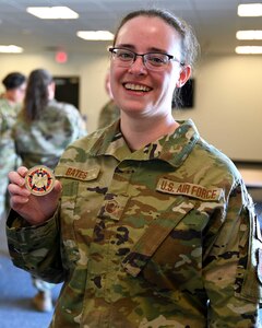 Master Sgt. Amanda Bates, program manager for the NHNG Counterdrug Task Force, shows off a coin presented to her by visiting Gen. David Hokanson, chief, National Guard Bureau, May 3, 2022, at Pease Air National Guard Base in Newington.