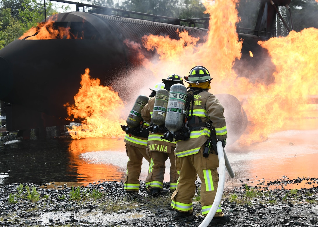 Three 316th Civil Engineer Squadron firefighters work together to extinguish a simulated aircraft fire at Joint Base Andrews, Md., May 2, 2022.