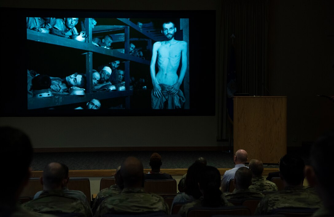 An image of a Holocaust victim is depicted on a large screen