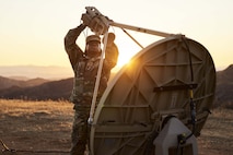 A Soldier performing maintenance on a satellite antenna.