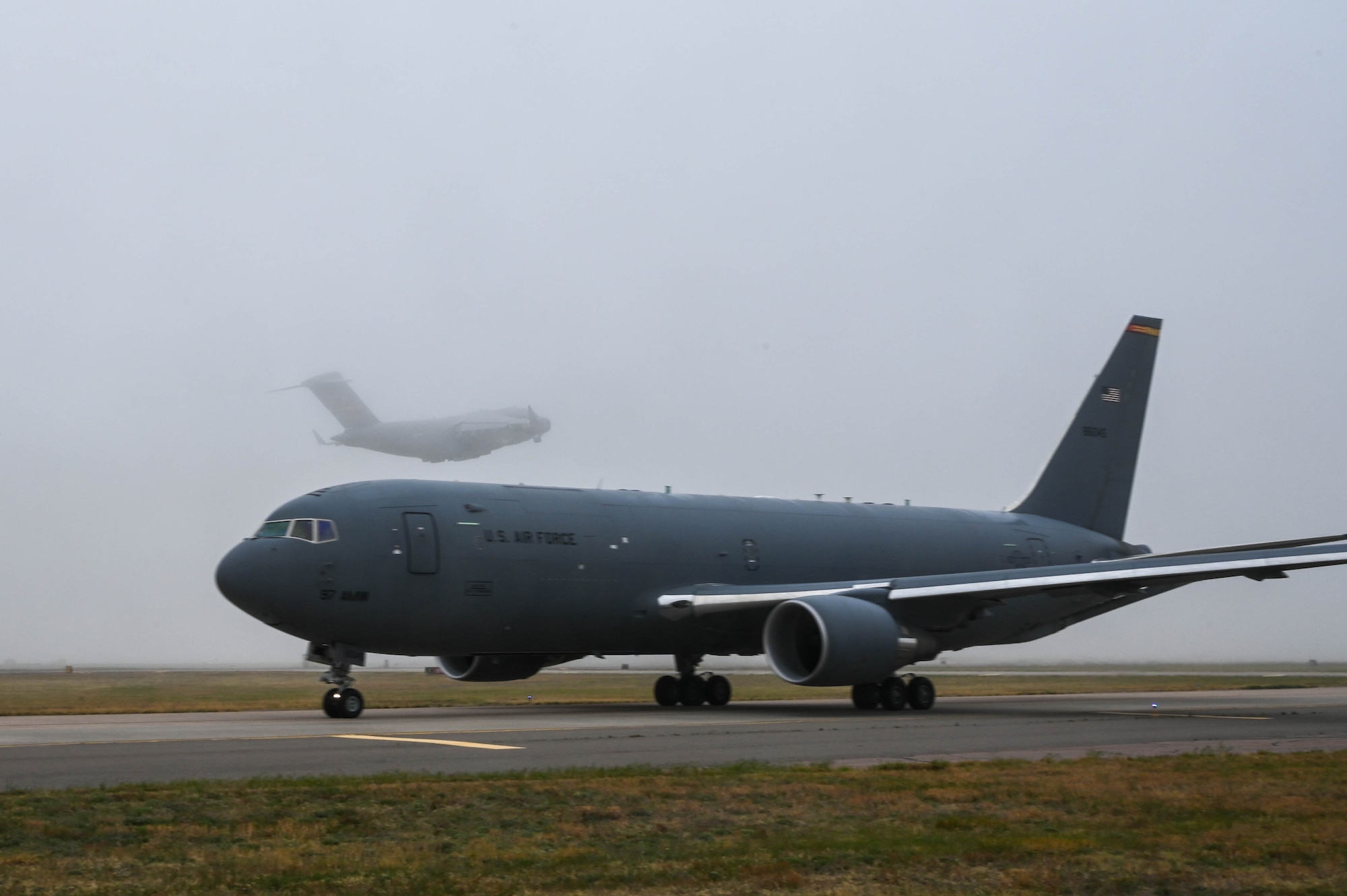 A C-17 Globemaster III takes off while a KC-46 Pegasus taxis on the flight line at Altus Air Force Base (AAFB), Oklahoma, May 4, 2022. Before the severe weather was projected to arrive at AAFB, 13 C-17s were successfully launched. (U.S. Air Force photo by Senior Airman Kayla Christenson)