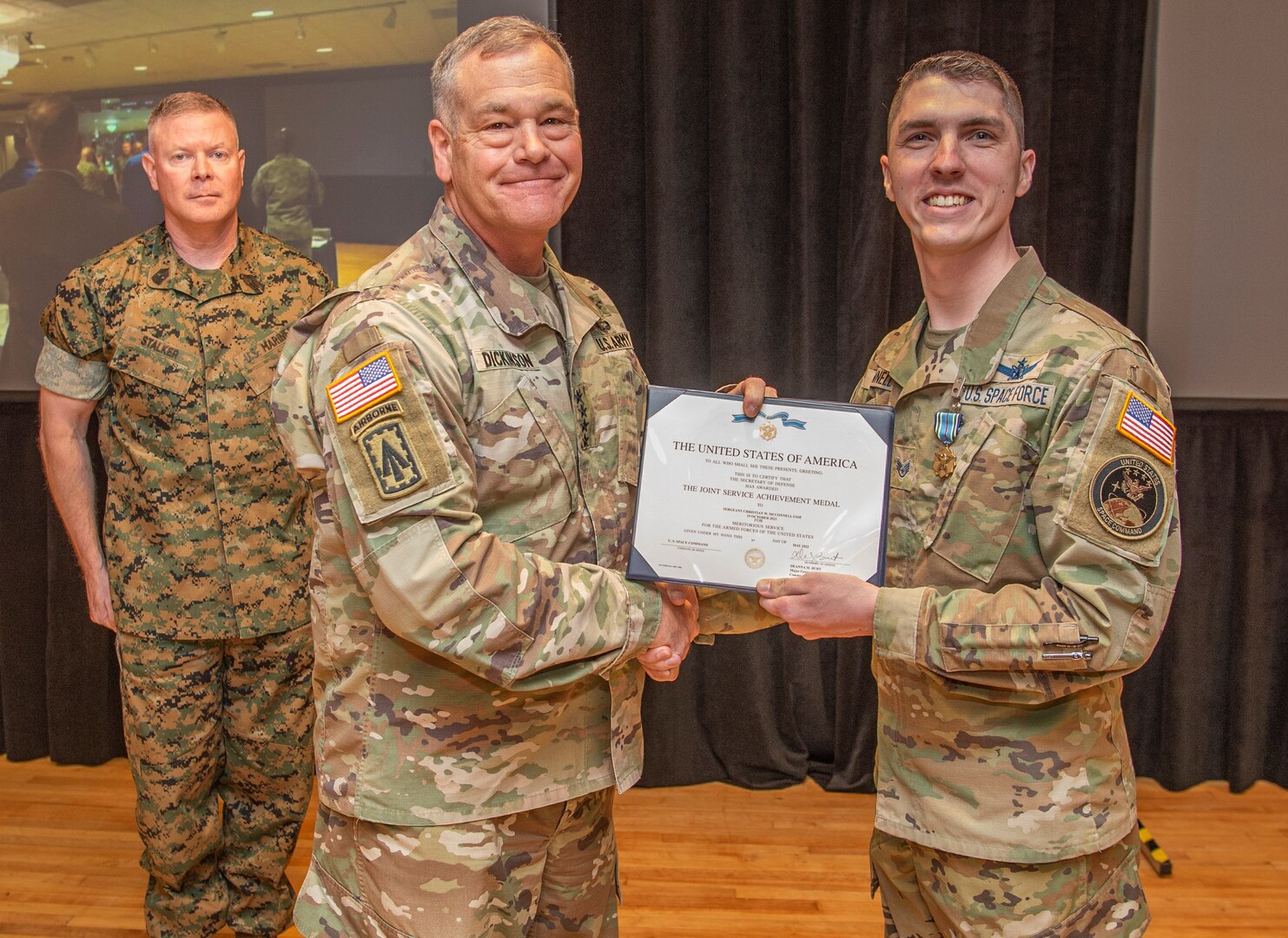 U.S. Army Gen. James Dickinson, U.S. Space Command commander, middle, presents U.S. Space Force Sgt. Christian McConnell, a Missile Warning Center crew technician for the Combined Force Space Component Command, right, a Joint Service Achievement Medal May 4, 2022, during a ceremony at Peterson Space Force Base, Colo.  McConnell received the medal for his quick thinking and efforts to provide emergency medical assistance to a fellow crewmember who suffered a sudden cardiac arrest at on Oct. 19, 2021. (U.S. Space Force photo by Petty Officer 1st Class John Wagner)