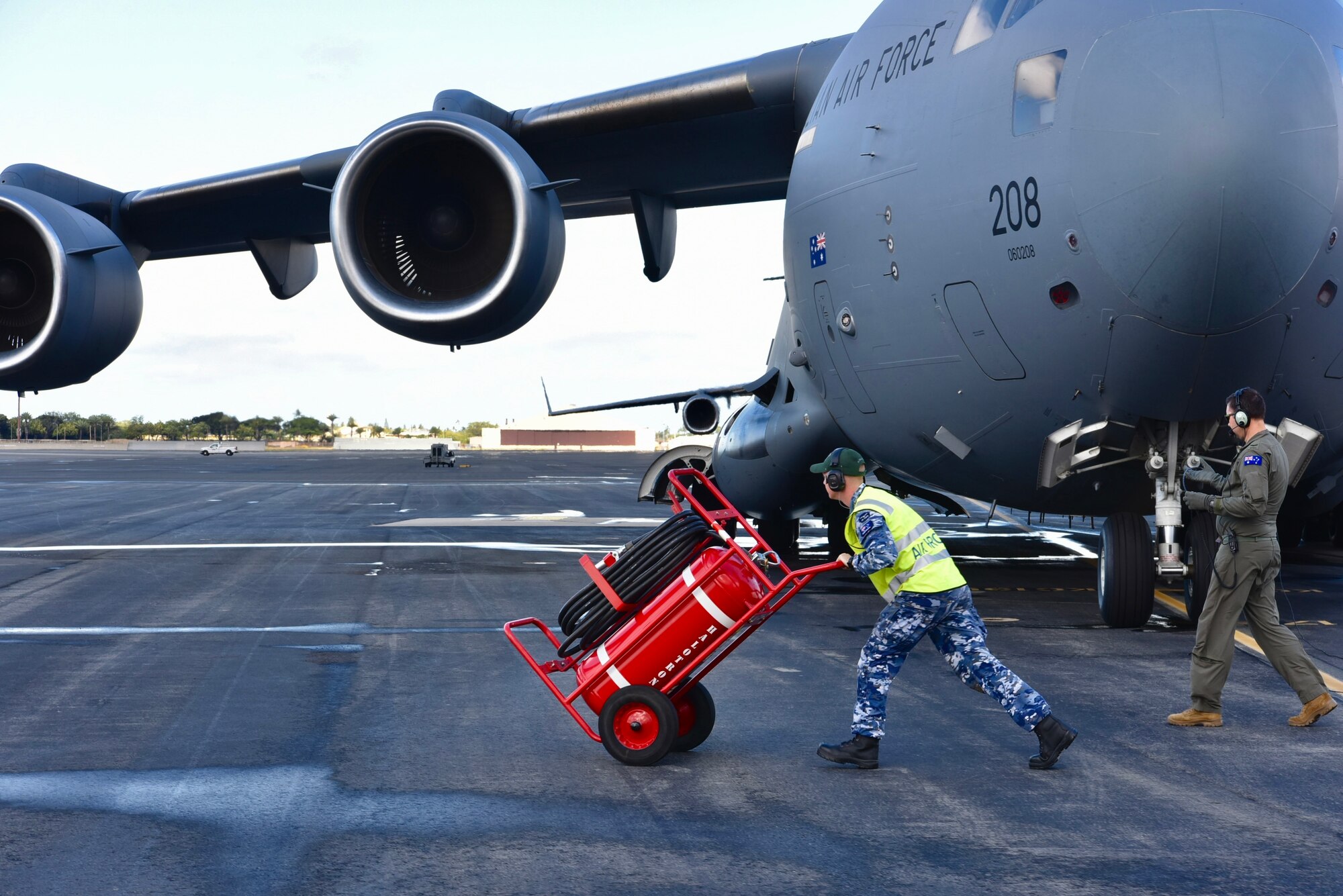 Royal Australian Air Force Leading Aircraftman Luke McAndrew, No. 36 Squadron aircraft technician, removes the flight line fire extinguisher while RAF Corporal Grant Vaughan, No. 36 Squadron loadmaster, finishes a pre-flight inspection before taking off for the first training mission of Exercise Global Dexterity 2022 at Joint Base Pearl Harbor-Hickam, Hawaii, May 3, 2022. The 15th Wing hosted the RAF as part of Exercise Global Dexterity 2022, where U.S. and Australian C-17s and aircrew can train and fly side-by-side to learn from each other. (U.S. Air Force photo by 1st Lt. Benjamin Aronson)