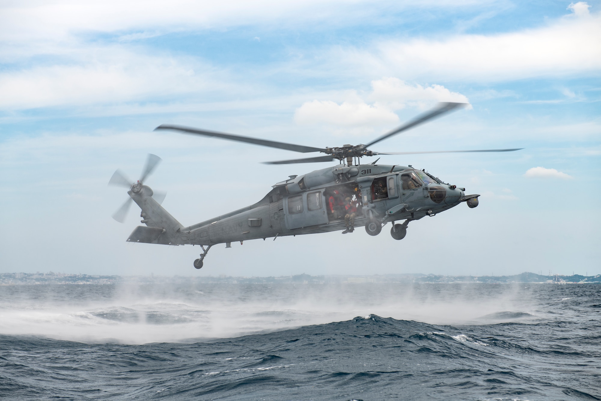 Airmen prepare to jump from a helicopter.