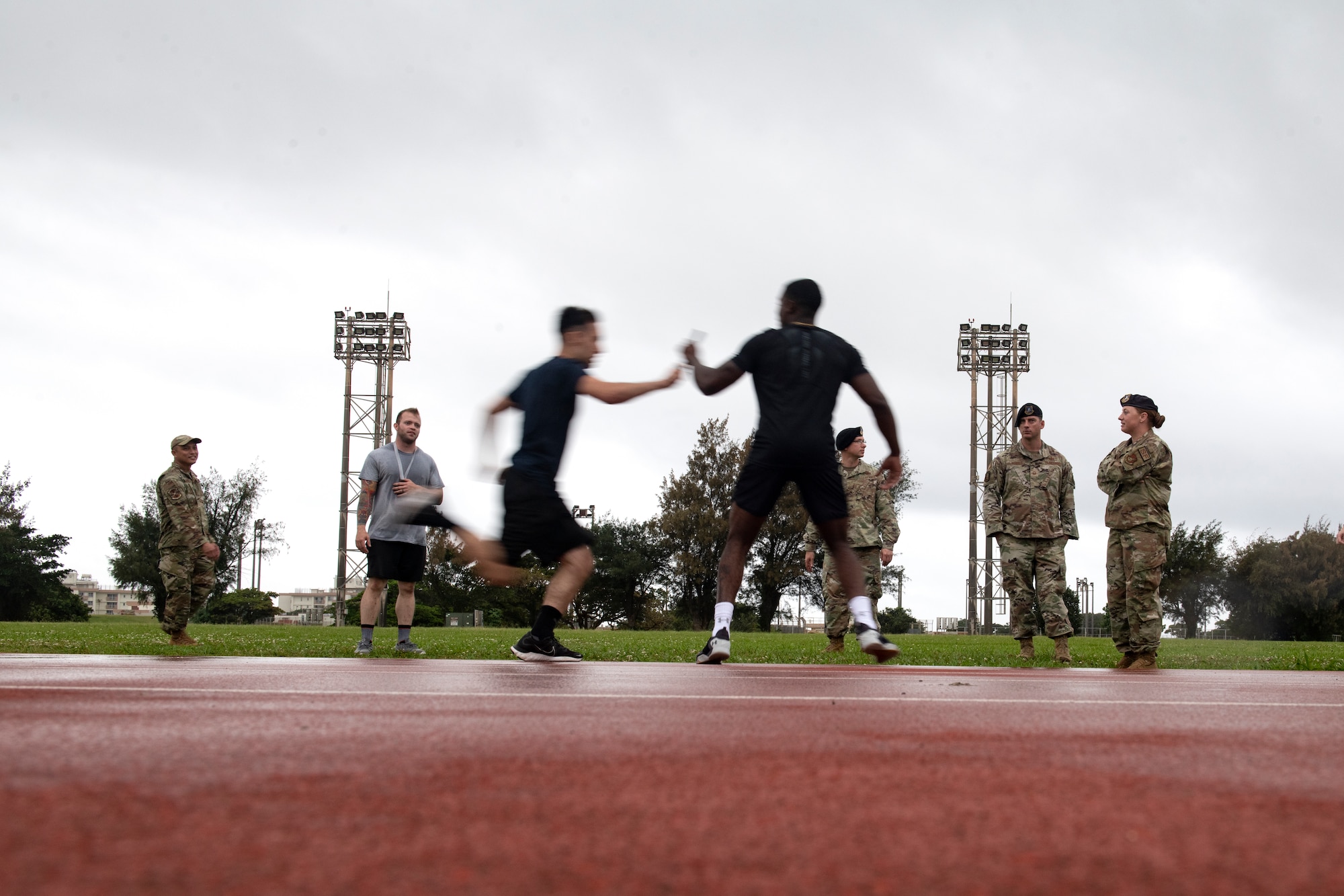 An Airman passes the baton to his partner during a relay race for the first annual Dorm Olympics at Kadena Air Base, Japan, April 29, 2022. The event is slated to be an annual occurrence, with the creators hoping they can push the idea to bases Air Force wide. (U.S. Air Force photo by Senior Airman Jessi Monte)