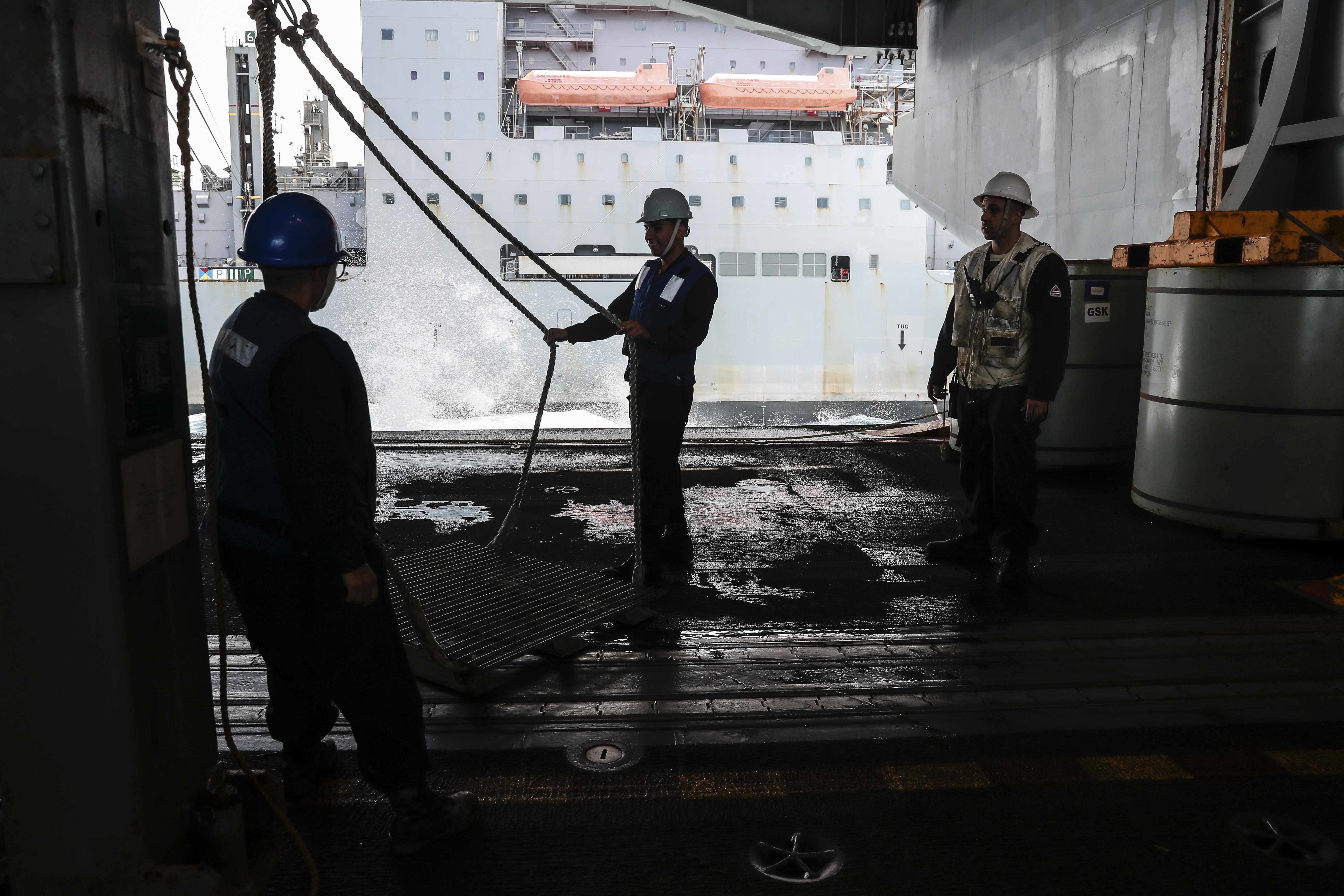Sailors stand by for cargo in the hangar bay aboard of the Nimitz-class aircraft carrier USS Abraham Lincoln (CVN 72) during a replenishment-at-sea
