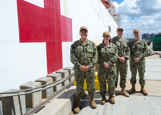 (Left to Right) Religious Program Specialist 2nd Class Evan Andrade, Lt. Jg. Wendy Byh-Jongejan, RP2 Daniel Tomaso, and Cmdr. Christopher Martin pose in front of the Military Sealift Command hospital ship USNS Mercy (T-AH 19) prior to a Pacific Partnership 2022 deployment at Naval Base San Diego, April 12. The Sailors make up the USNS Mercy’s religious staff. Mercy can steam to assist anywhere to provide relief as a symbol of Navy Medicine’s abilities around the world, and must be in a five-day-activation status in order to support missions over the horizon, and be ready, reliable and resilient to support mission commanders.(U.S. Navy photo by Mass Communication Specialist Seaman Raphael McCorey)