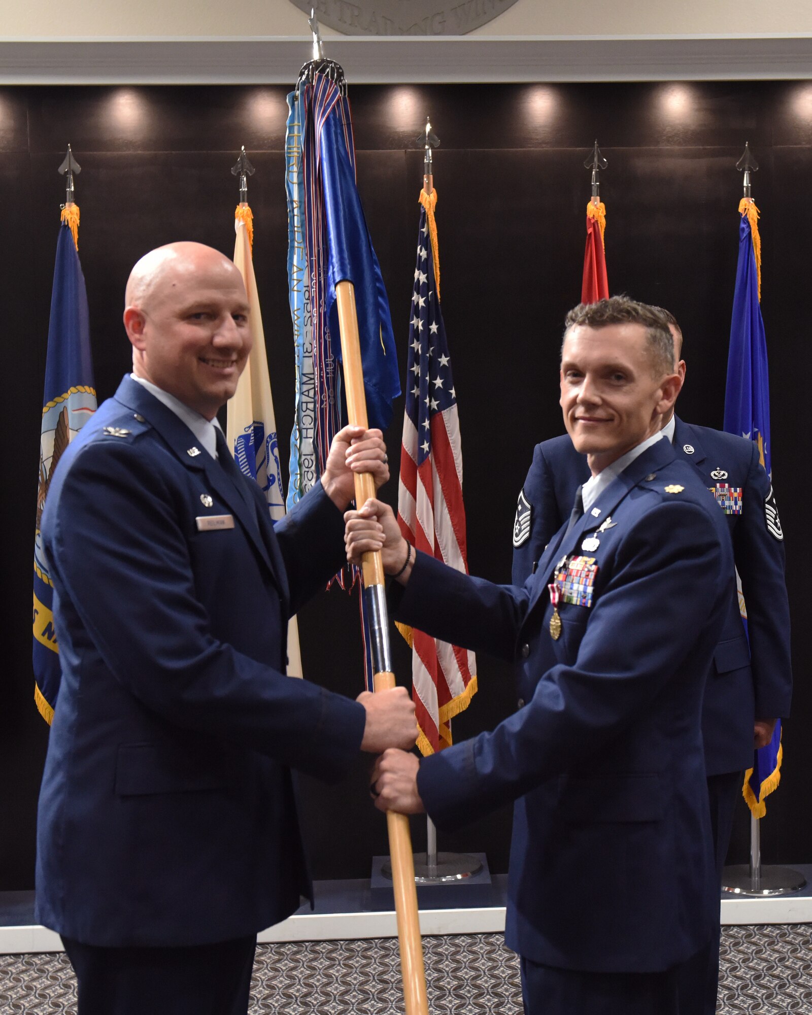 U.S. Air Force Maj. William Bennett (right), 17th Communications Squadron outgoing commander, relinquishes command to Col. Matthew Reilman, 17th Training Wing commander,  during the 17th CS change of command ceremony, at the Powell Event Center, Goodfellow Air Force Base, Texas, May 5, 2022.  Passing the guidon physically represents the symbolism of passing the squadron responsibilities to the next commander. (U.S. Air Force photo by Airman 1st Class Zachary Heimbuch)