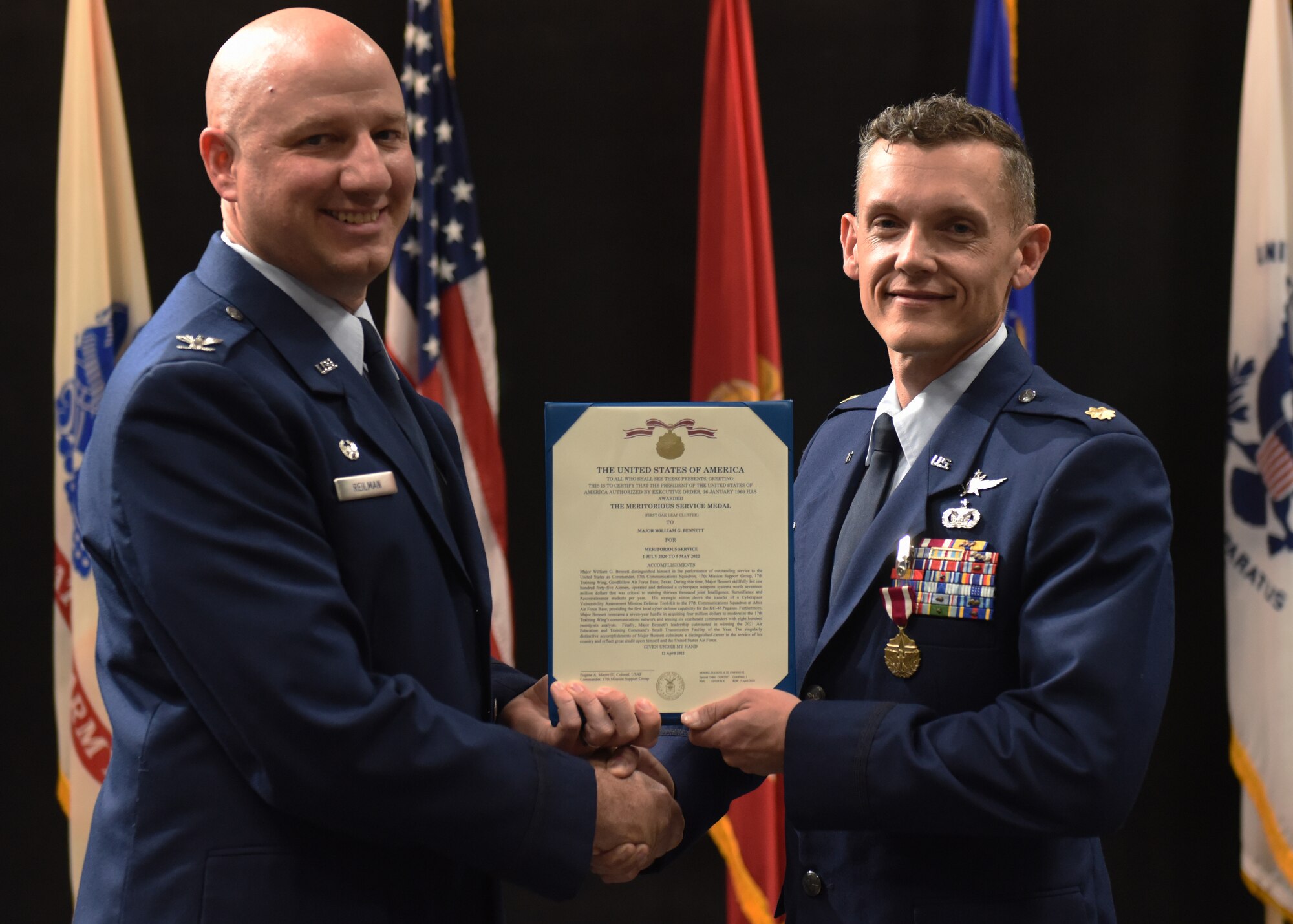 U.S. Air Force Maj. William Bennett (right), 17th Communications Squadron outgoing commander, receives the Meritorious Service Medal from Col. Matthew Reilman, 17th Training Wing commander, during the 17th CS change of command ceremony, at the Powell Event Center, Goodfellow Air Force Base, Texas, May 5, 2022. The 17th CS welcomed incoming commander, Maj. Dexter Webb from the 51st Fighter Wing in Osan Air Base, Republic of Korea. (U.S. Air Force photo by Airman 1st Class Zachary Heimbuch)
