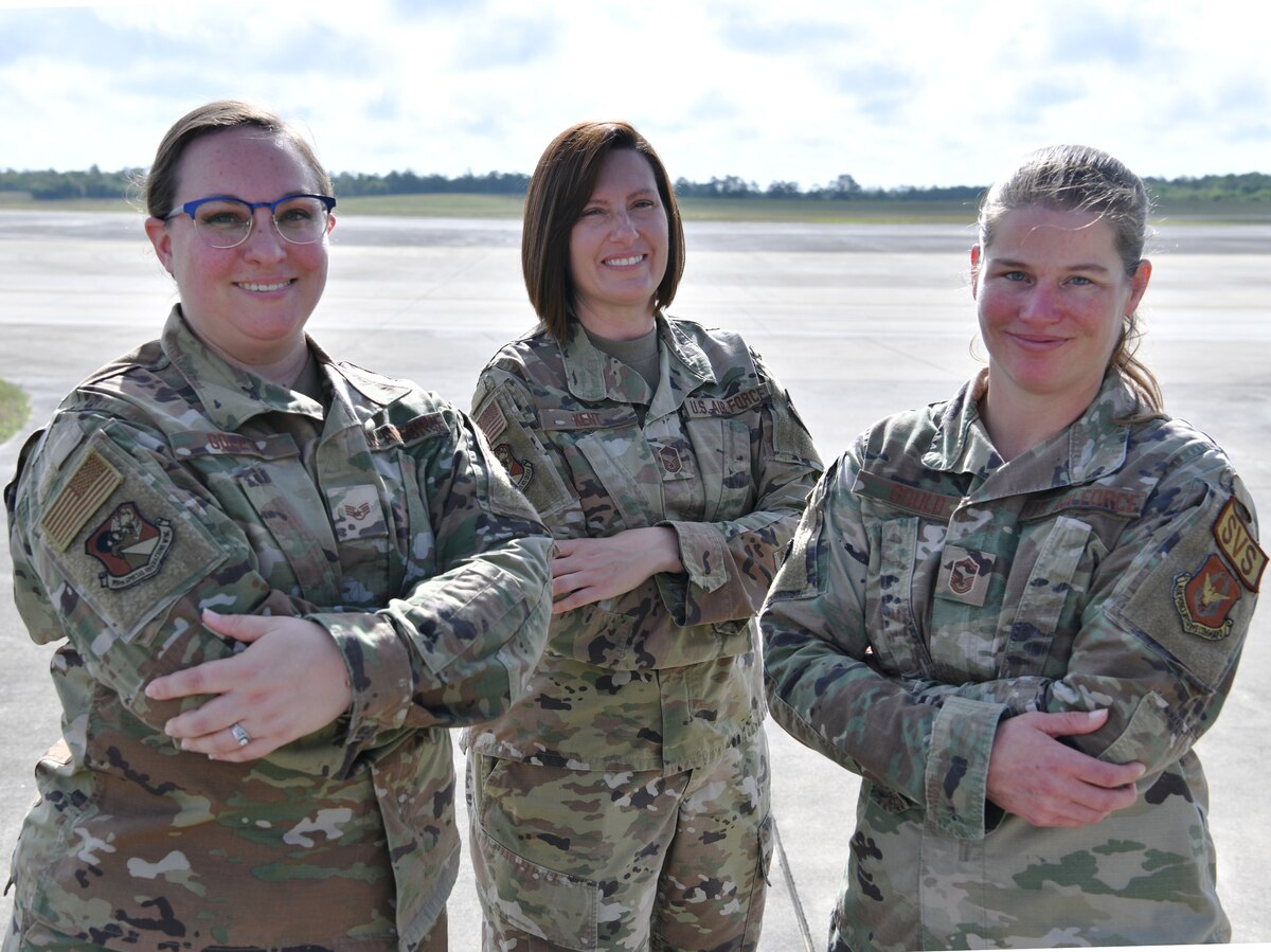 Three military women stand near the flight line for a group photo