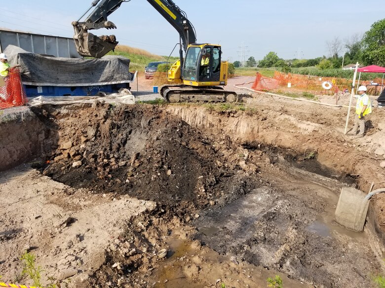 Construction equipment digging in brown dirt.