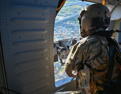 Army Specialist Arthur Allen, assigned to the 3rd Battalion, 142nd Aviation Regiment of the New York National Guard, fires an M240B machine gun from a hovering UH-60L Black Hawk helicopter at Fort Drum, New York, April 28, 2022, during annual training. The battalion is preparing to mobilize in June and deploy to Kuwait.