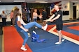 Danielle Wilson, counselor, Santa Rosa Ranch School, Tucson, Ariz., breaks a board in two after kicking it as part of a demonstration with the Taekwondo Army World Class Athlete team, April 27, Fort Carson, Colo. The demonstration was part of the Phoenix Recruiting Battalion’s Educators Tour of the base that provided a comprehensive orientation and overview of Fort Carson for the attendees U.S. Army Photo by Mike Scheck, USAREC Public Affair