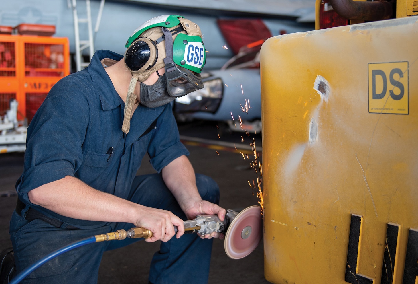 Aviation Support Equipment Technician Seaman Apprentice Zachary Owen, from Frederick, Maryland, uses an angle grinder to remove corrosion from a forklift in the hangar bay of the Nimitz-class aircraft carrier USS Harry S. Truman (CVN 75), Dec. 15, 2021.