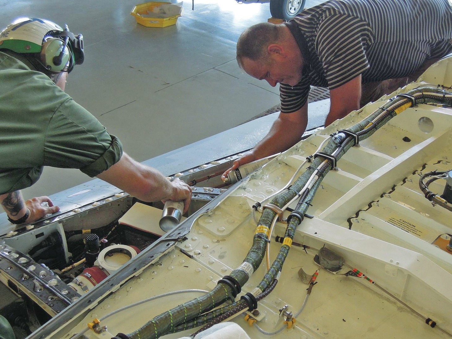 Bret Sourbrine, right, F/A-18 Fleet Support Team East Coast Coordinator, works with a maintainer to apply NavGuard IV corrosion prevention compound to an F/A-18E Super Hornet at Naval Air Station Oceana in July 2018 as part of a field test of the compound’s effectiveness.