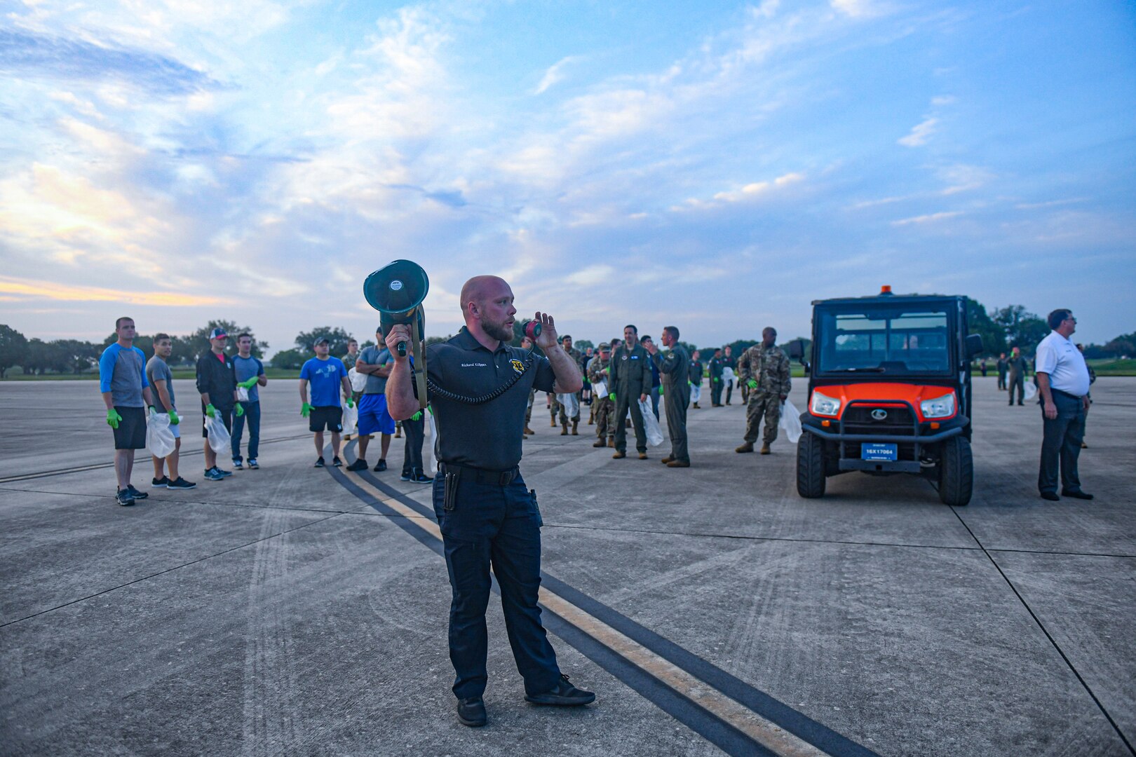 AF Civilian using bullhorn to give instructions to others lining up for a FOD walk.