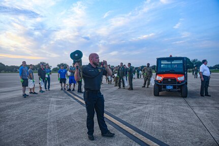 AF Civilian using bullhorn to give instructions to others lining up for a FOD walk.