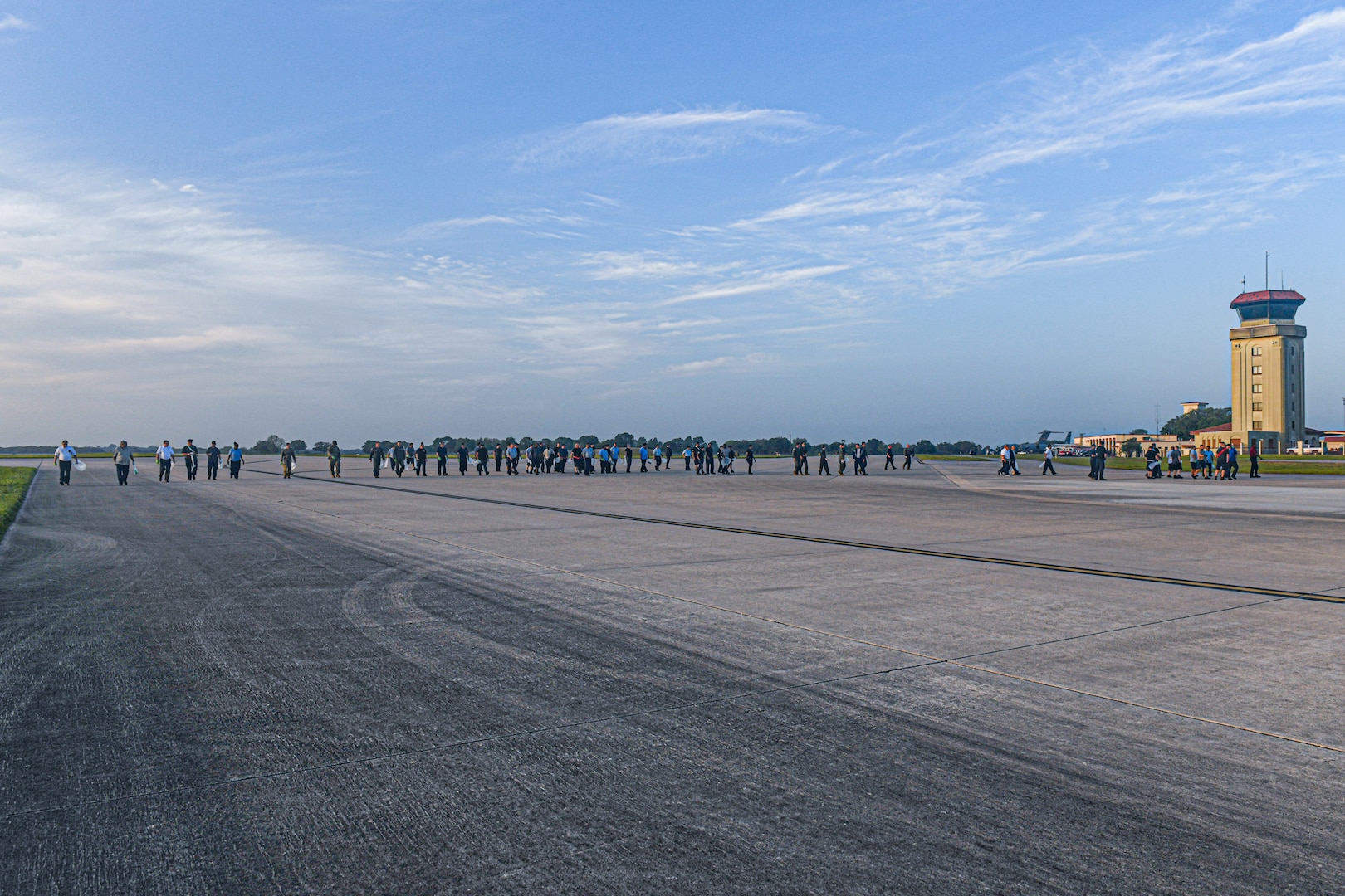 Dozens of members line up across the runway to continue a FOD walk.