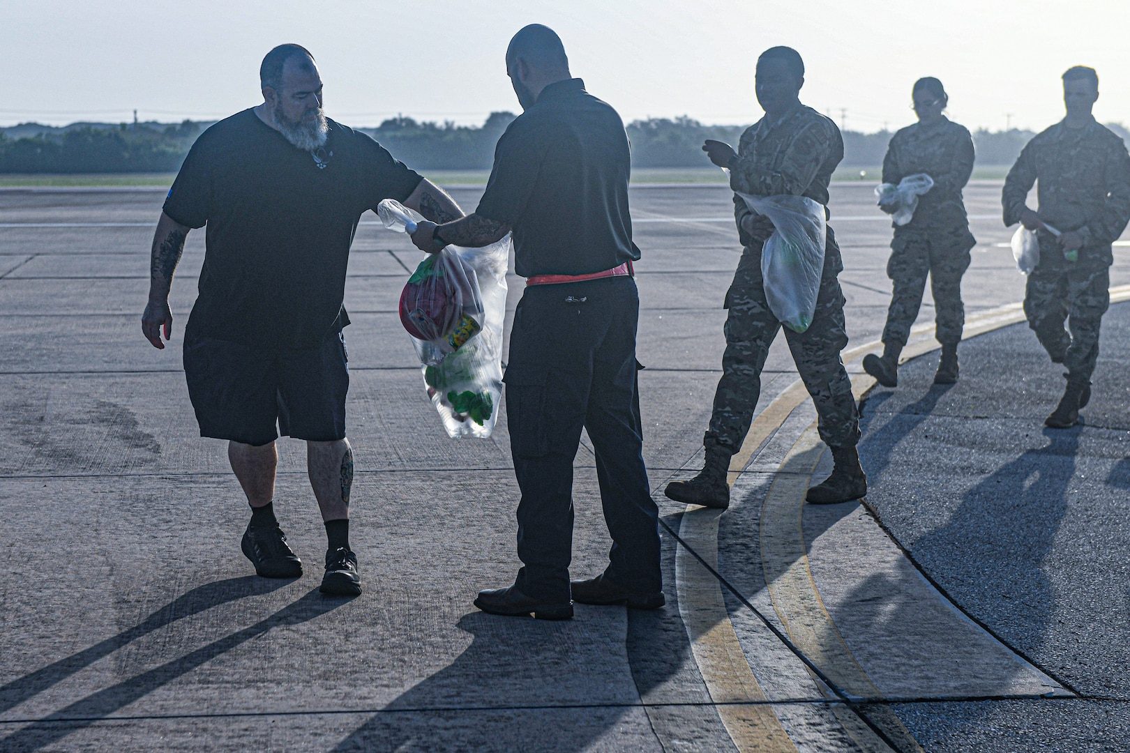Airmen and AF Civilians place items into a collections bag.