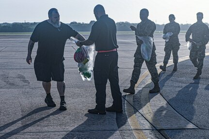 Airmen and AF Civilians place items into a collections bag.