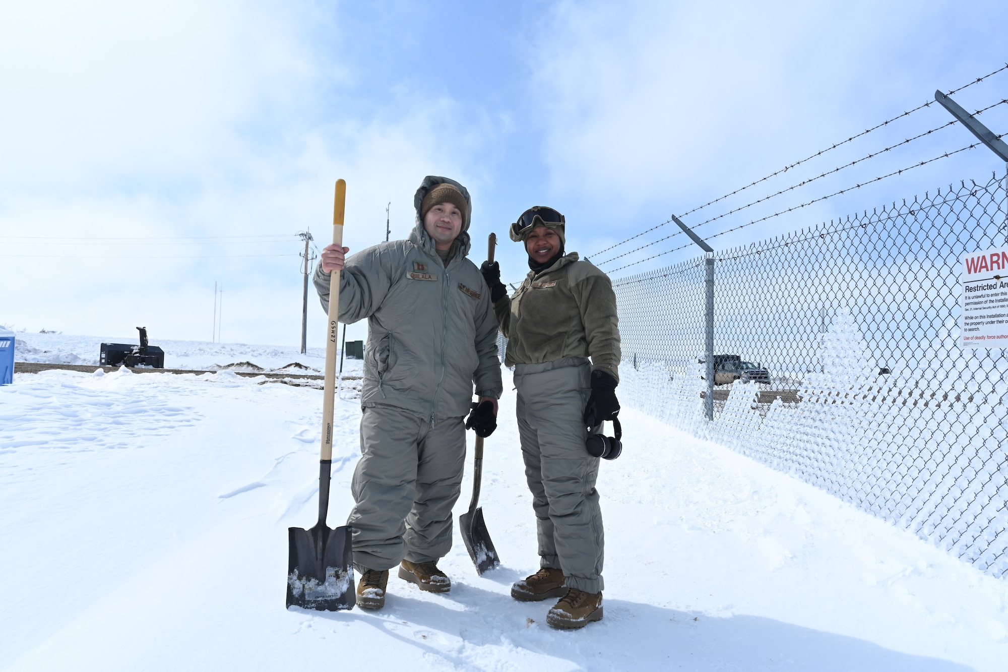 Two U.S. Air Force Airmen assigned to the 91st Missile Wing take a break from snow clearing and ditch digging at a launch facility at Minot Air Force Base, North Dakota, April 26, 2022.