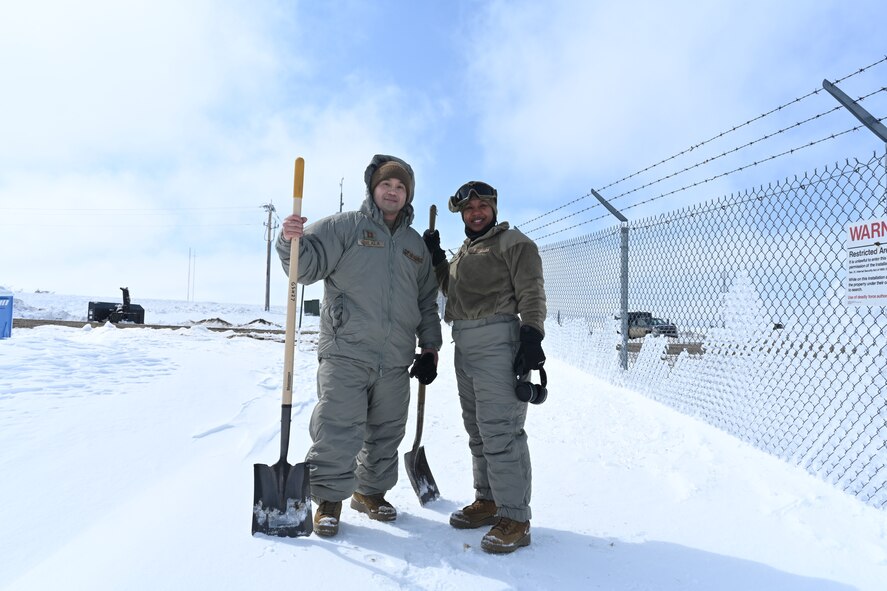 Two U.S. Air Force Airmen assigned to the 91st Missile Wing take a break from snow clearing and ditch digging at a launch facility at Minot Air Force Base, North Dakota, April 26, 2022.