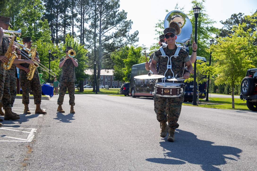 U.S. Marine Corps Lance Cpl. Ezequiel Gonzalez, Lance Cpl. Daniel Watter and Sgt. William Emrich, musicians with the 2nd Marine Aircraft Wing (MAW) Brass Band, march around the 2nd MAW Brass Band during a drive-thru concert at Grants Landing Community Center, Marine Corps Air Station (MCAS) Cherry Point North Carolina, April 27, 2022. Throughout the performance, sweet treats, goody bags, and resources for military families were handed out in honor of Month of the Military Child. (U.S. Marine Corps photo by Lance Cpl. Lauralle Walker)