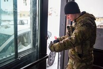 Airman 1st Class Jullian Baxter, 5th Security Forces Defender, checks IDs at the main gate on Minot Air Force Base, North Dakota April 19, 2022.