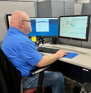 Scott Wilkerson at his desk using the Local Retail Buy Request and Tracking System database.