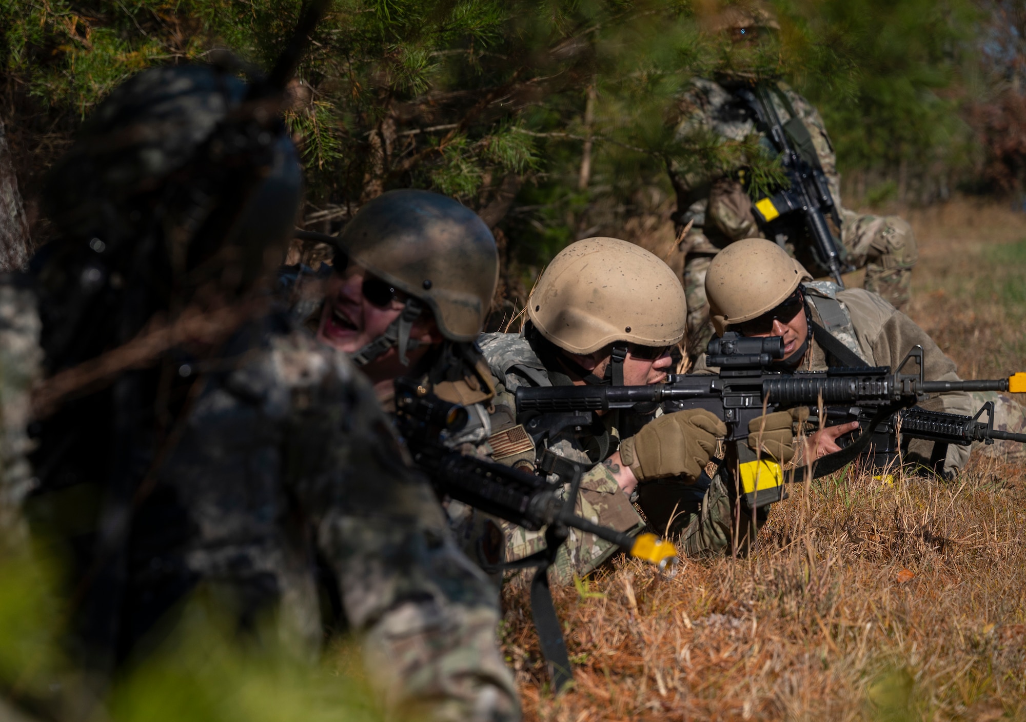 U.S. Air Force Field Craft Hostile students lay prone as they engage enemy forces during a field training exercise at Joint Base McGuire-Dix-Lakehurst, New Jersey, Nov. 19, 2021. FCH places students in realistic and strenuous training scenarios used to teach skills such as weapons control, combative techniques, communications, mounted and dismounted individual and team movements, and land navigation. (U.S. Air Force photo by Senior Airman Bryan Guthrie)